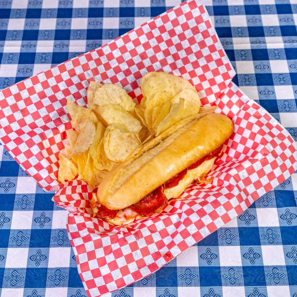 A Big Dog's Pizza pepperoni sub with melted cheese and a side of potato chips.