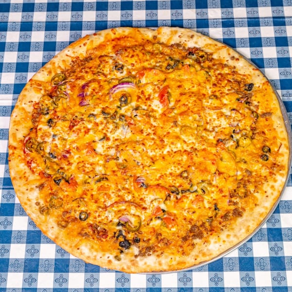 A Big Dog's Pizza with cheese, ground beef, olives, red onions, and jalapeños on a blue checkered tablecloth.